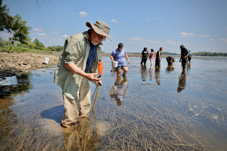 Roland Williams looks into the water with volunteers behind him