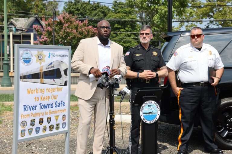Troy Singleton speaks behind a podium next to two officers