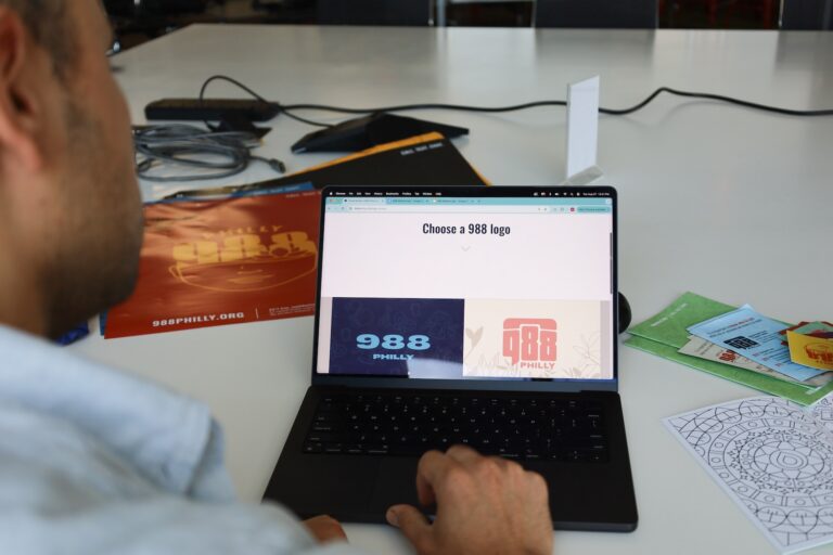 Miguel Hernandez, art director at Jeme Agency, demonstrates how the online 988 Philly awareness and design catalog serves as a tool for people looking to spread awareness about the national mental health and suicide crisis lifeline on Aug. 27, 2024.