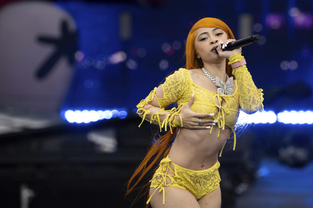 A female rapper performs on stage holding a microphone to her mouth
