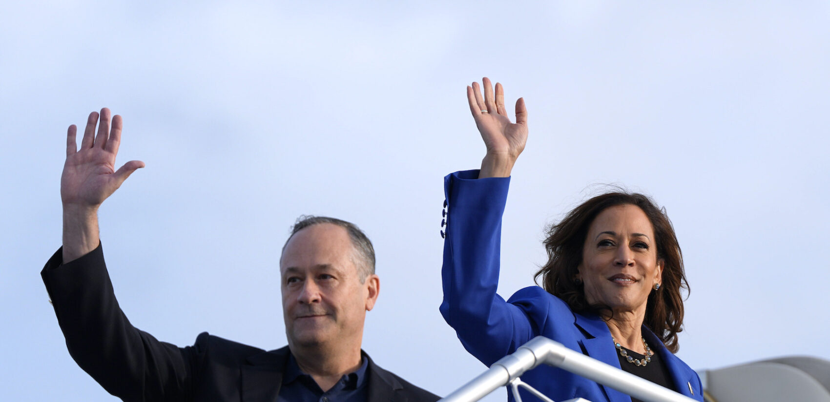 Doug Emhoff and Kamala Harris waving as they get onto the airplaine