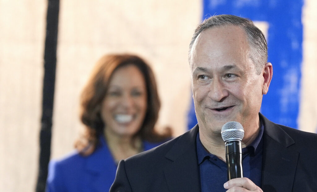 Election 2024 Harris Doug Emhoff speaking into a microphone as Kamala Harris watches