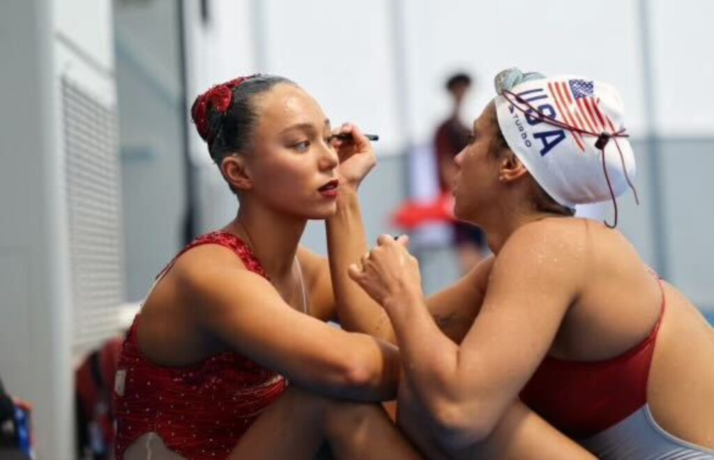 Megumi-Field-wilmington On the left, Megumi Field receives makeup from her teammate in Japan as she prepares for the 2023 World Championships, where they secured the first U.S. medal on the world stage in 16 years. (Courtesy of Alyssa Jacobs)