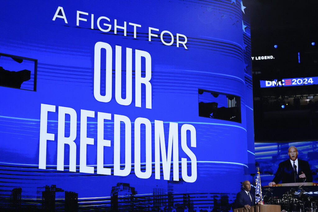 Election 2024 DNC Cory Booker speaks in front of a screen reading A FIGHT FOR OUR FREEDOMS