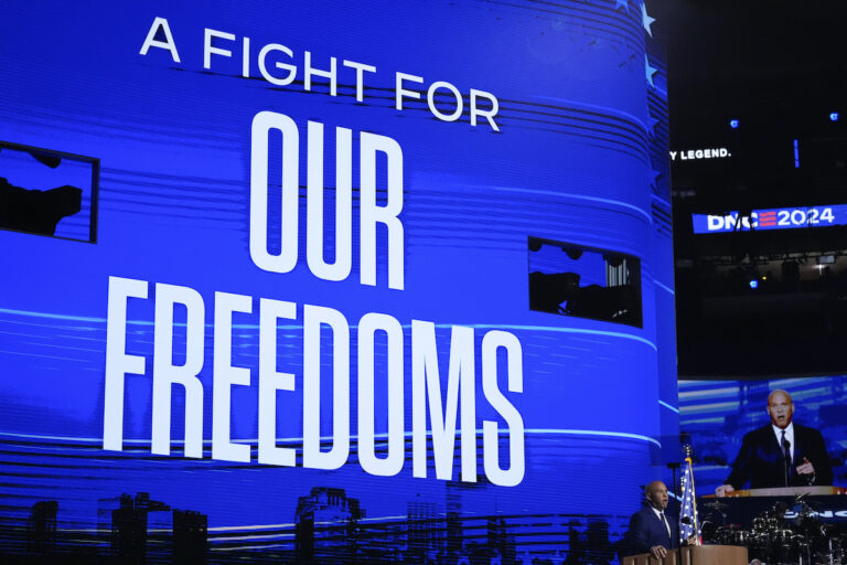 Cory Booker speaks in front of a screen reading A FIGHT FOR OUR FREEDOMS