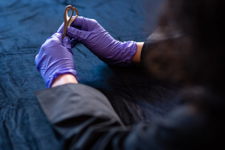 Person wearing purple gloves handles an unidentified medical instrument