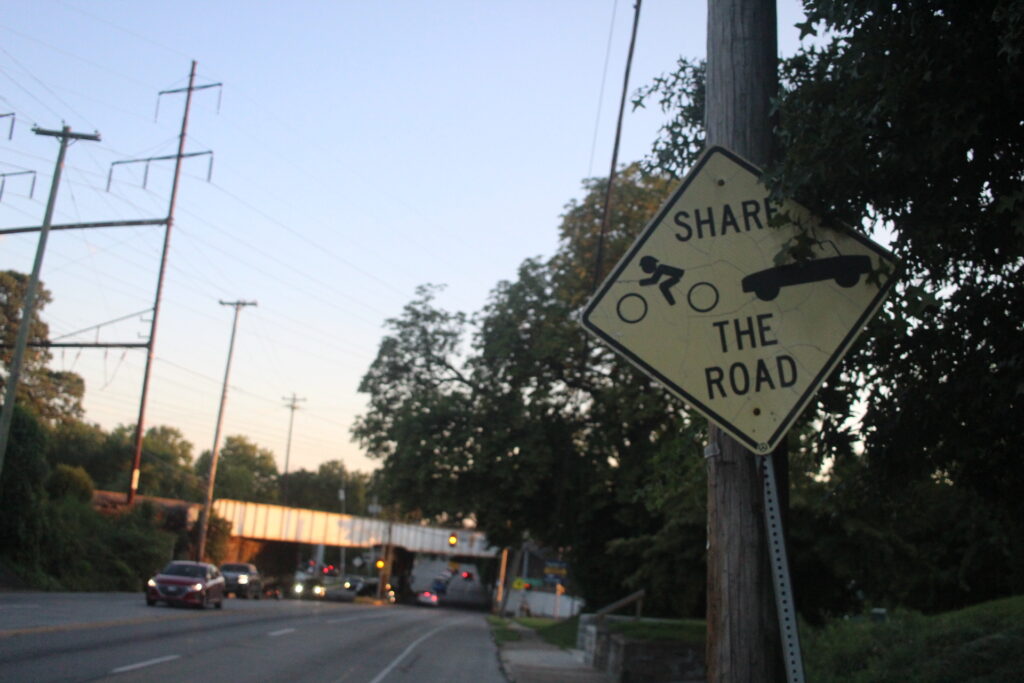 chester-pike-share-the-road a sign on Chester Pike reads Share the Road and has symbols for a cyclist and car