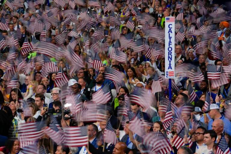 A crowd waves American flags