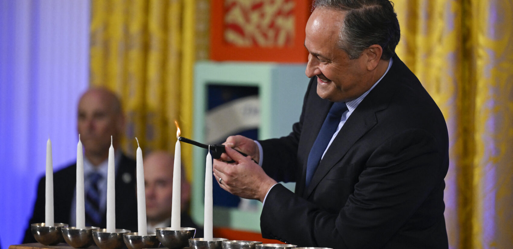 Doug Emhoff lighting a menorah