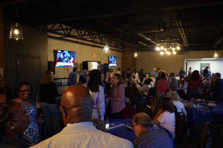 About 100 people gathered at tables and standing