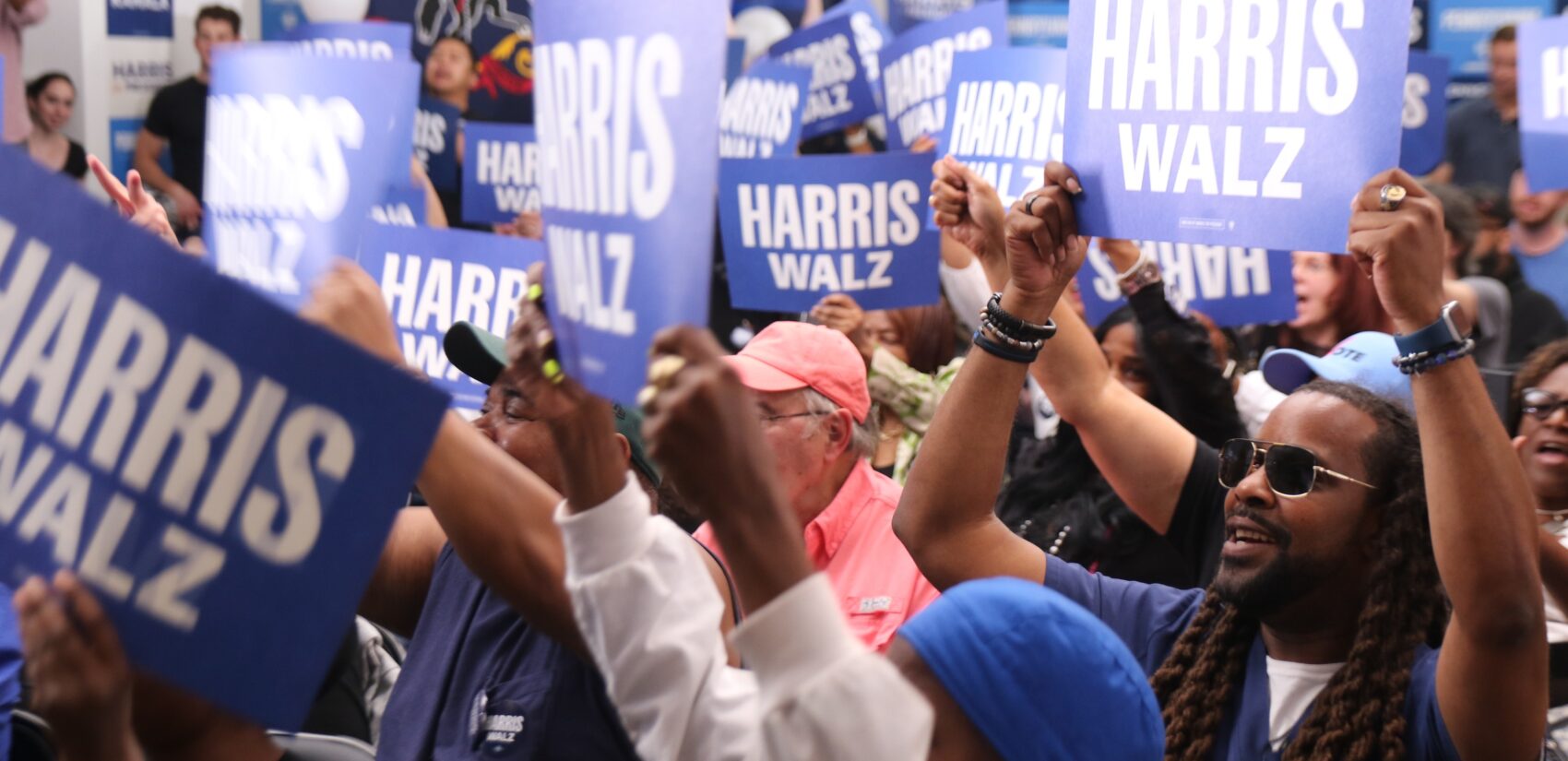 People holding Harris Walz signs