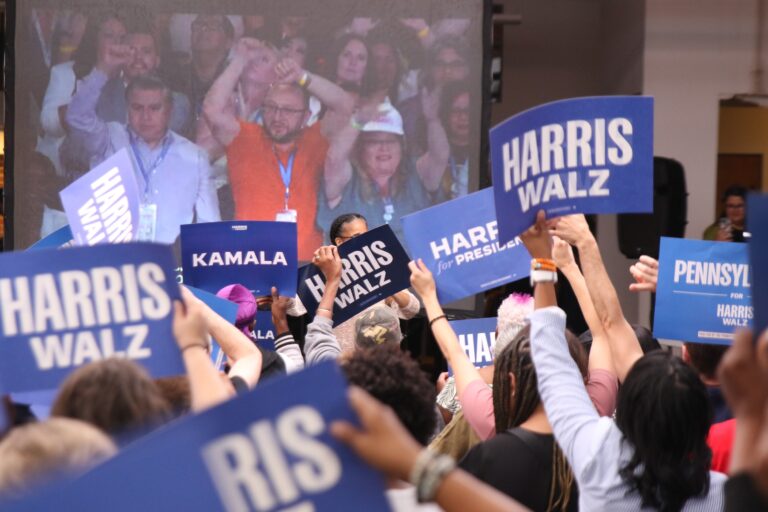 People holding Harris Walz signs