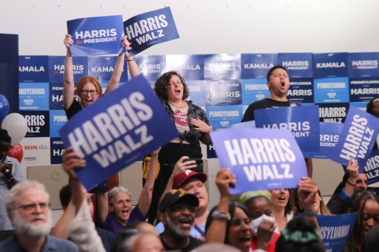 People holding Harris Walz signs