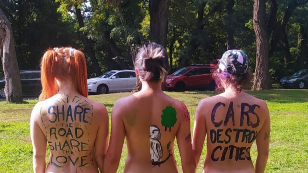 philly-naked-bikeride-backs-2024-08-23 3 topless women with their backs to the camera with messages painted on themselves