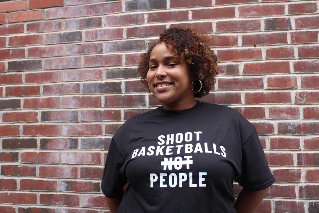 Candace Wright, representing Shoot Basketballs Not People, stands in front of a brick wall