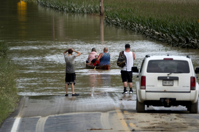 People paddle through a flooded area of New York following Tropical Storm Debby