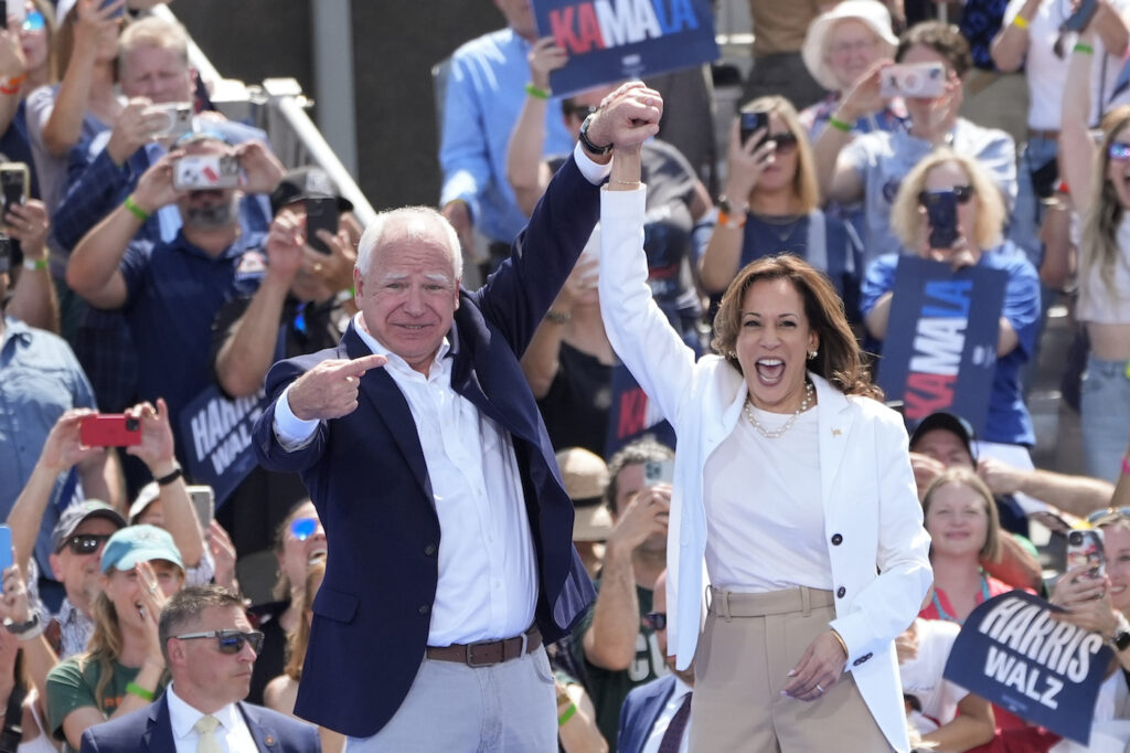 Kamala Harris and Tim Walz raising their hands together on stage