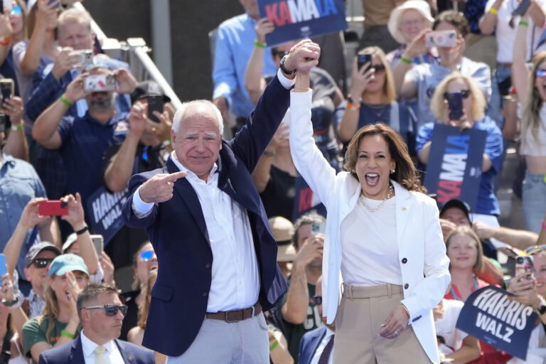 Kamala Harris and Tim Walz raising their hands together on stage