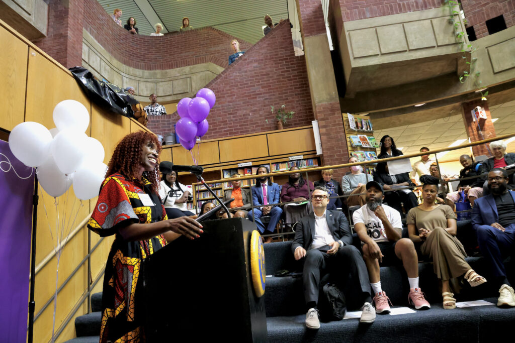 Val Gay speaking at a podium