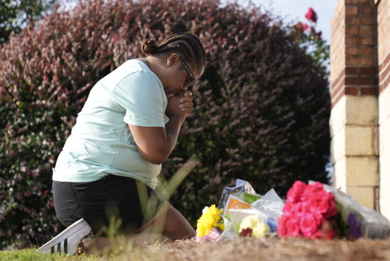 Linda Carter, of Grayson, Ga., kneels near Apalachee High School to place flowers as she mourns for the slain students and teachers on Thursday, Sept. 5, 2024, in Winder, Ga.