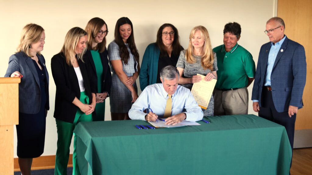 Carney-EV-bill-signing-2024-09-17 John Carney signs legislation surrounded by others