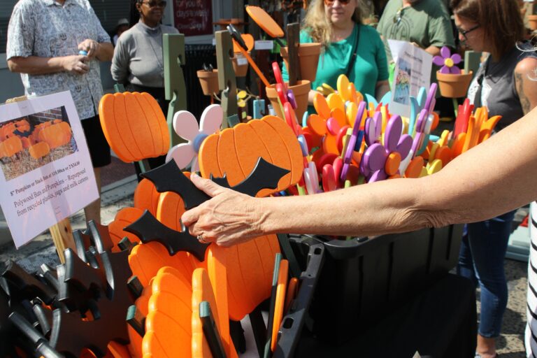 a person looks through colorful signs in the shapes of pumpkins and flowers