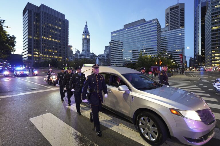 Officers walk aside a hearse in the street