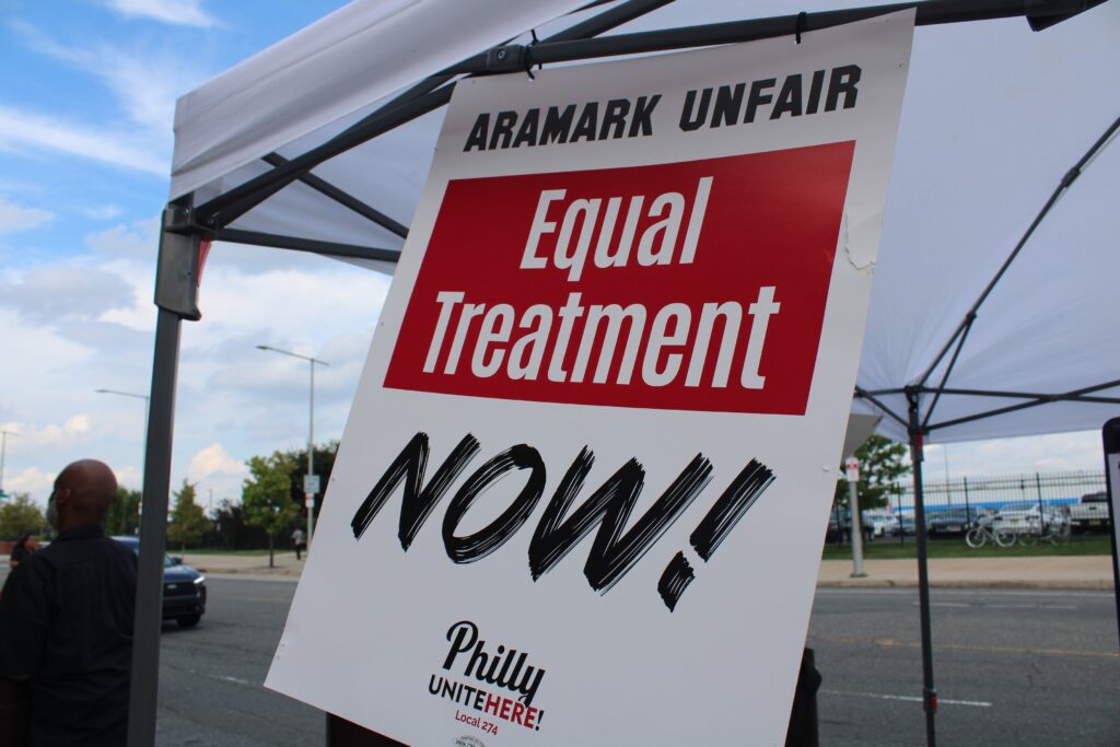 a sign reads ARAMARK UNFAIR EQUAL TREATMENT NOW!
