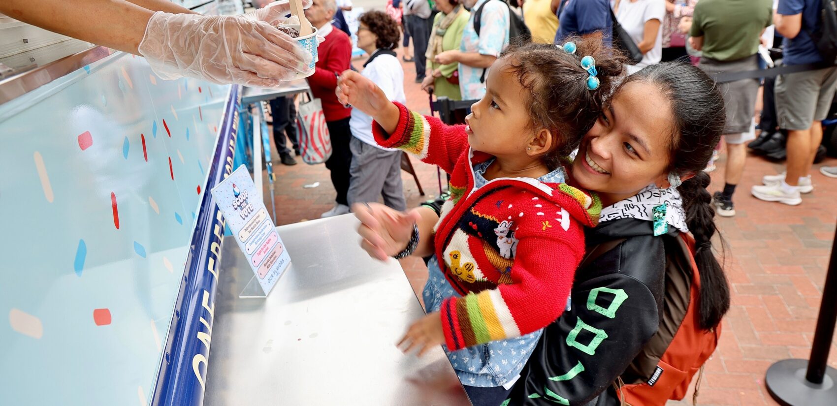 Ella Simmons holds her daughter, who is reaching out for ice cream at the truck