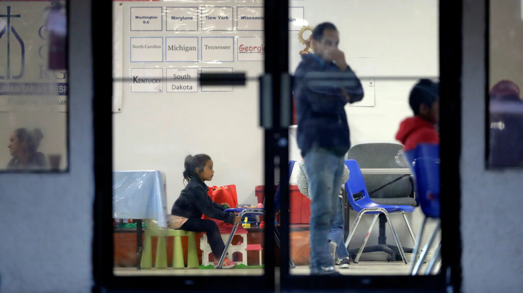 catholic-charities-texas-2018 a person stands and a child sits in an immigration support center