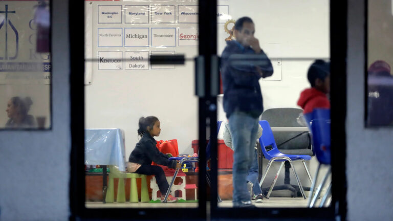 a person stands and a child sits in an immigration support center