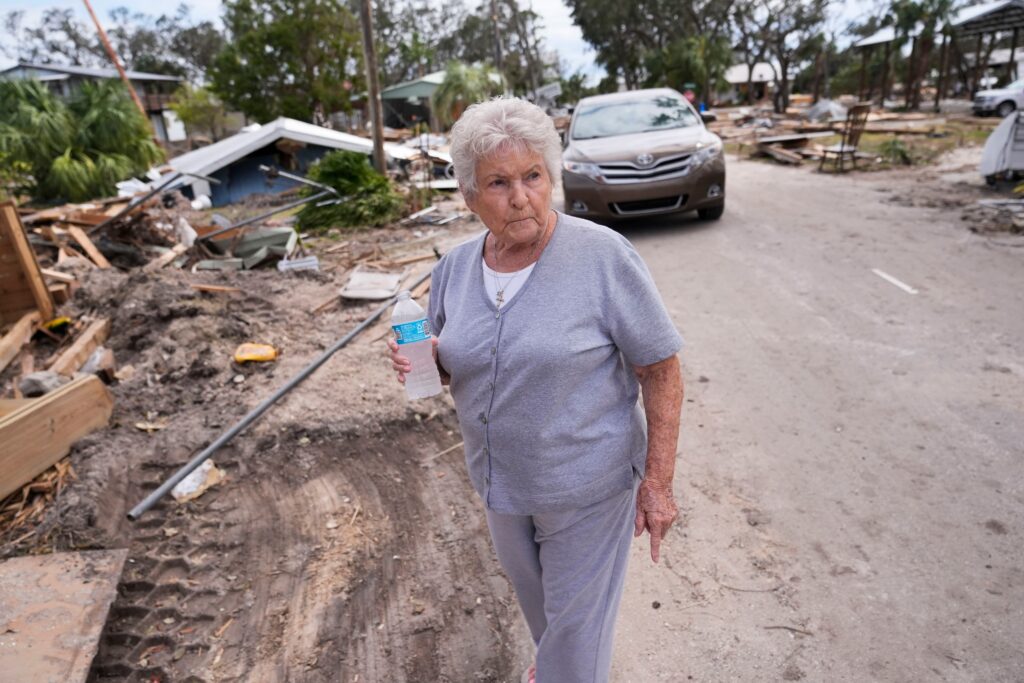 hurricane-helene-damage Elsie Hicks walks with a water bottle among storm damage