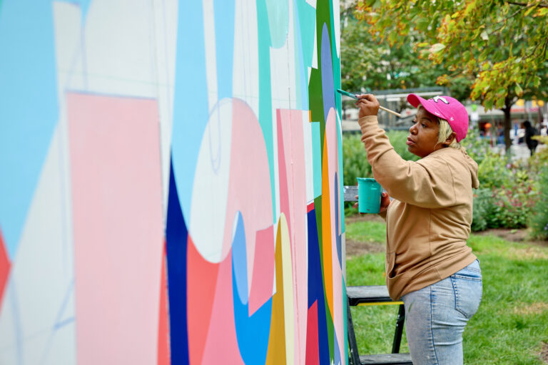 Woman paints a mural at Love Park