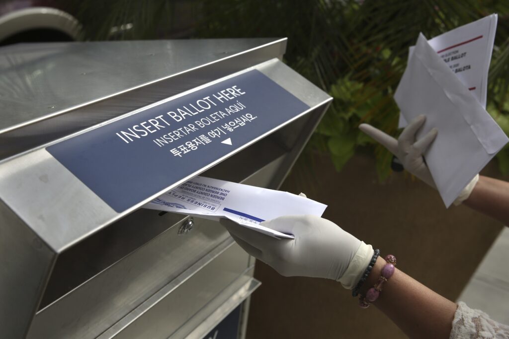 New Jersey Election Ballot Dispute A woman wearing gloves drops off a mail ballot at a drop box in Hackensack, N.J., on July 7, 2020.