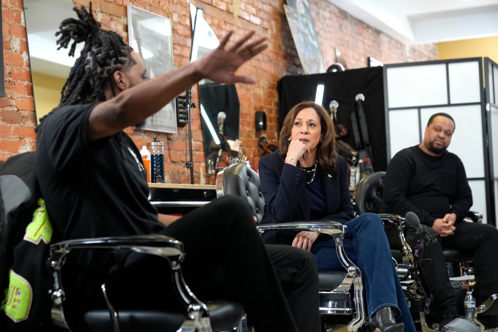 Kamala Harris sits and listens at a barbershop