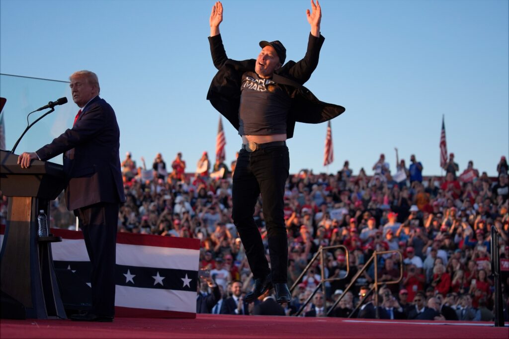 trump-musk-2024-10-05 Elon Musk jumps in the air next to Donald Trump onstage