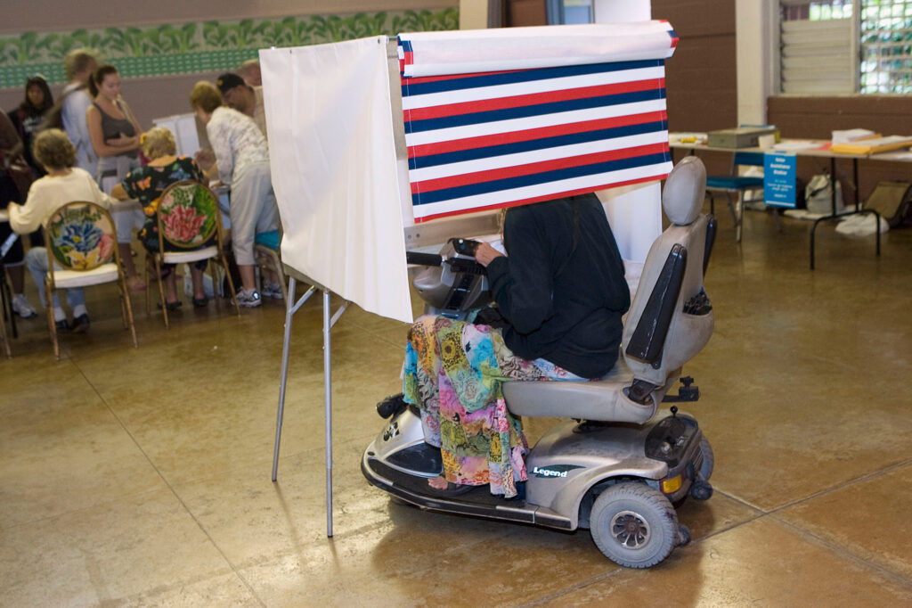 voter-wheelchair-2008-11-04 A woman in a motorized wheelchair casts her vote