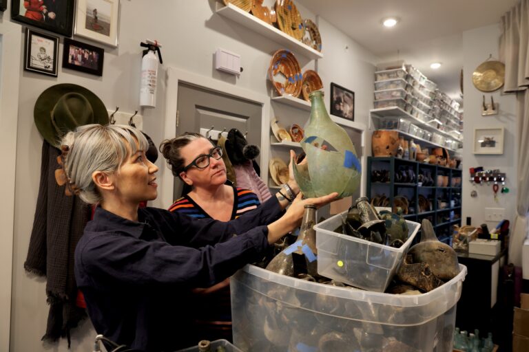 Composer Melissa Dunphy (left) and librettist Jacqueline Goldfinger admiire a glass bottle excavated from a privy pit on Callowhill Street. Dunphy's experience as an amateur archaeologist inspired the opera, ''Alice Tierney,''  about a “dissipated woman” who was murdered on Dunphy's property in 1880. (Emma Lee/WHYY)