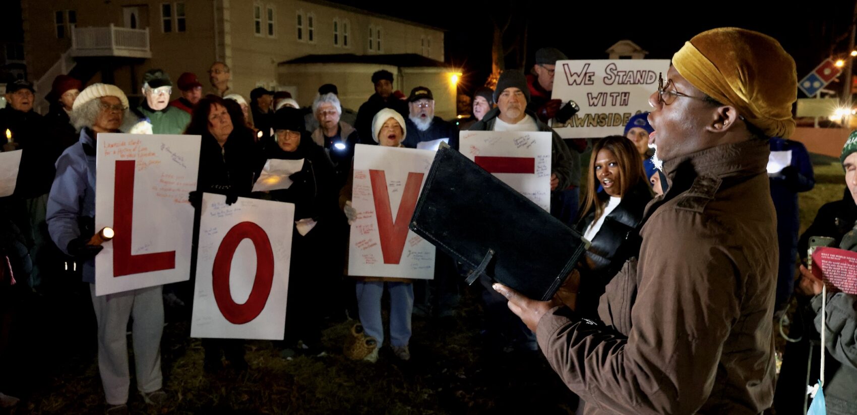 Lawnside resident Charles McNeil sings, and residents hold four signs reading LOVE