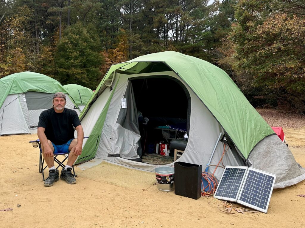Tharros-Village-delaware-3 Danny Rickapauth sits by a tent