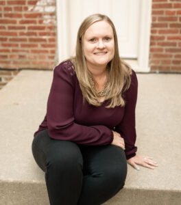 Jessica Welch posing for a photo while sitting on the front stoop of a house