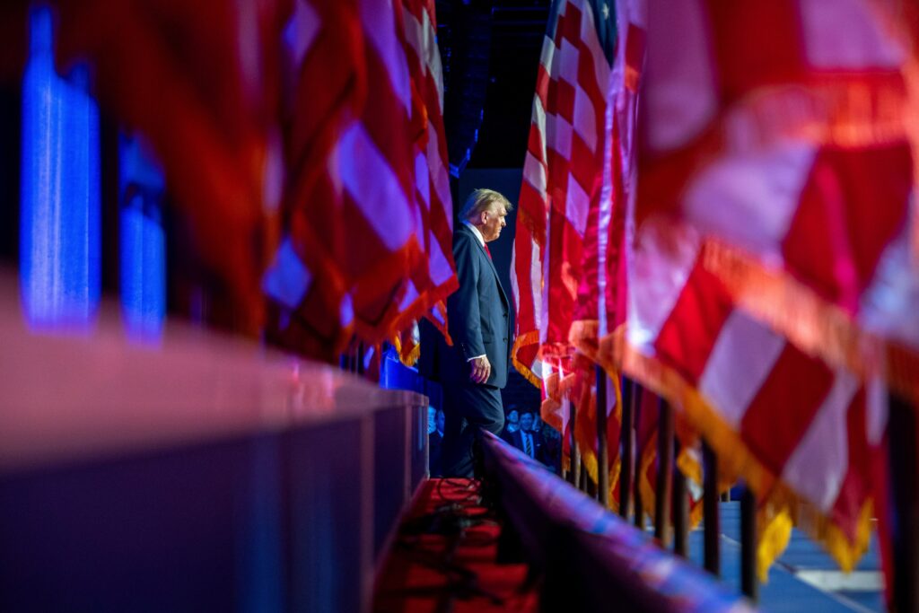 donald-trump-2024-11-06-standing Donald Trump standing in sight of multiple U.S. flags
