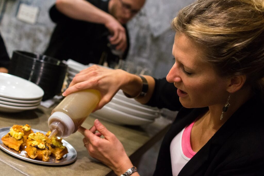 Kate Jacoby pours sauce on food
