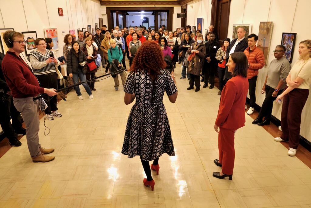 Val Gay speaks to a crowd in the gallery