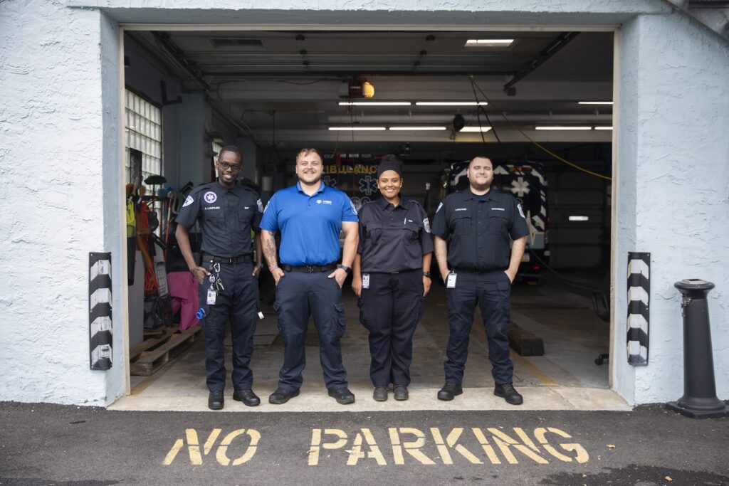 EMTs No Parking A group photo of 4 EMTS posing at their station