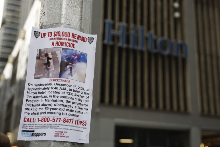 A Reward poster hung up on a light pole in front of the hotel