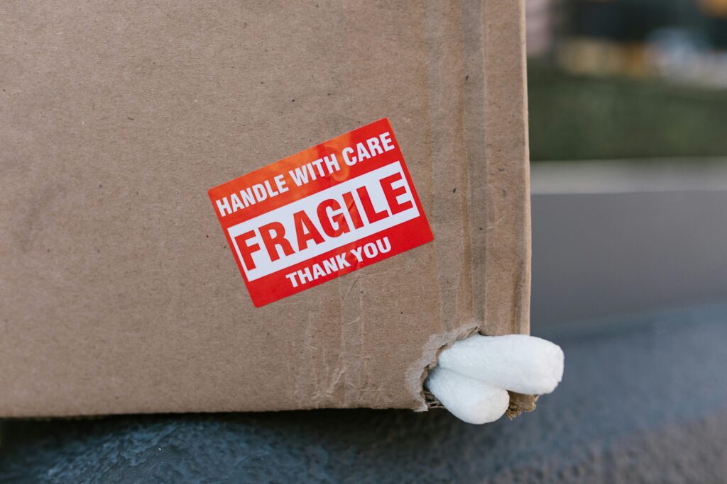 cardboard-box-packing-peanuts A cardboard box with packing peanuts poking out and a sticker reading HANDLE WITH CARE FRAGILE THANK YOU