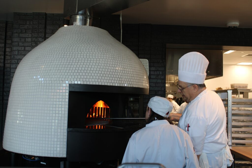 mccc-hospitality-institute-10 Two chefs put pizza in an oven
