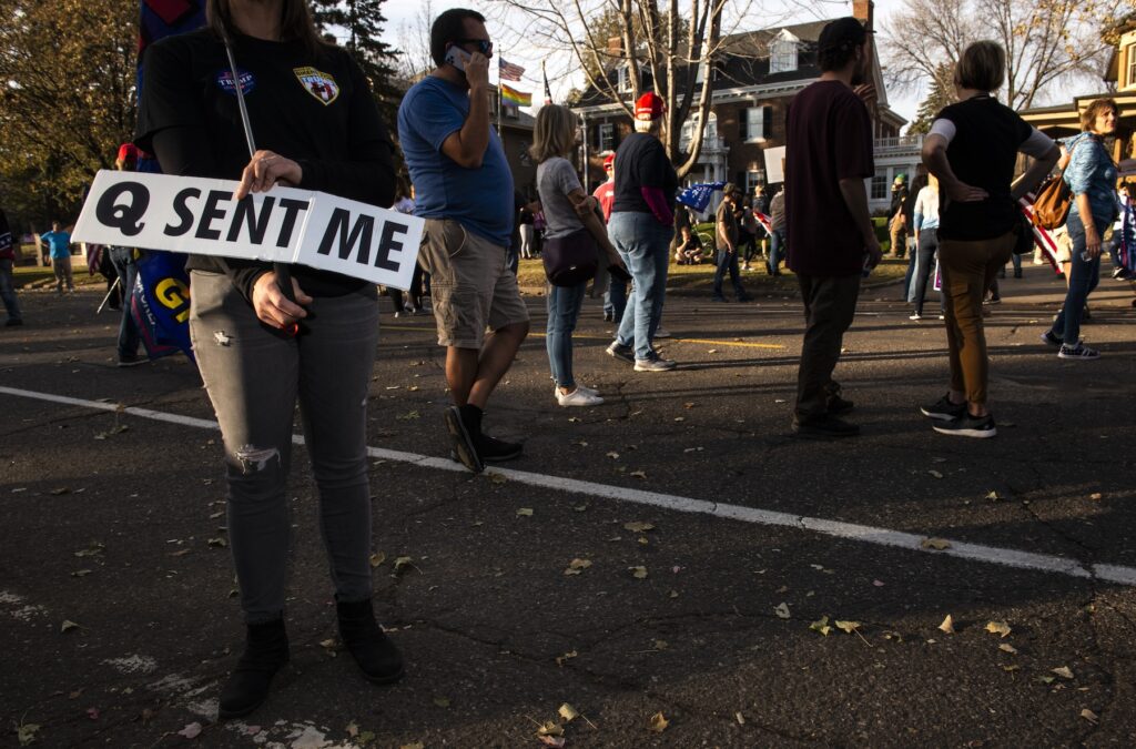 Woman holds a sign referencing the QAnon conspiracy
