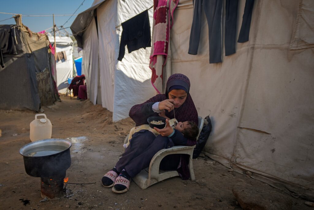 palestinian-camp-gaza-strip-2024-12-01 A 16-year-old feeds a baby at a camp for displaced Palestinians